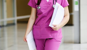 nurse walking with paperwork in pink scrubs