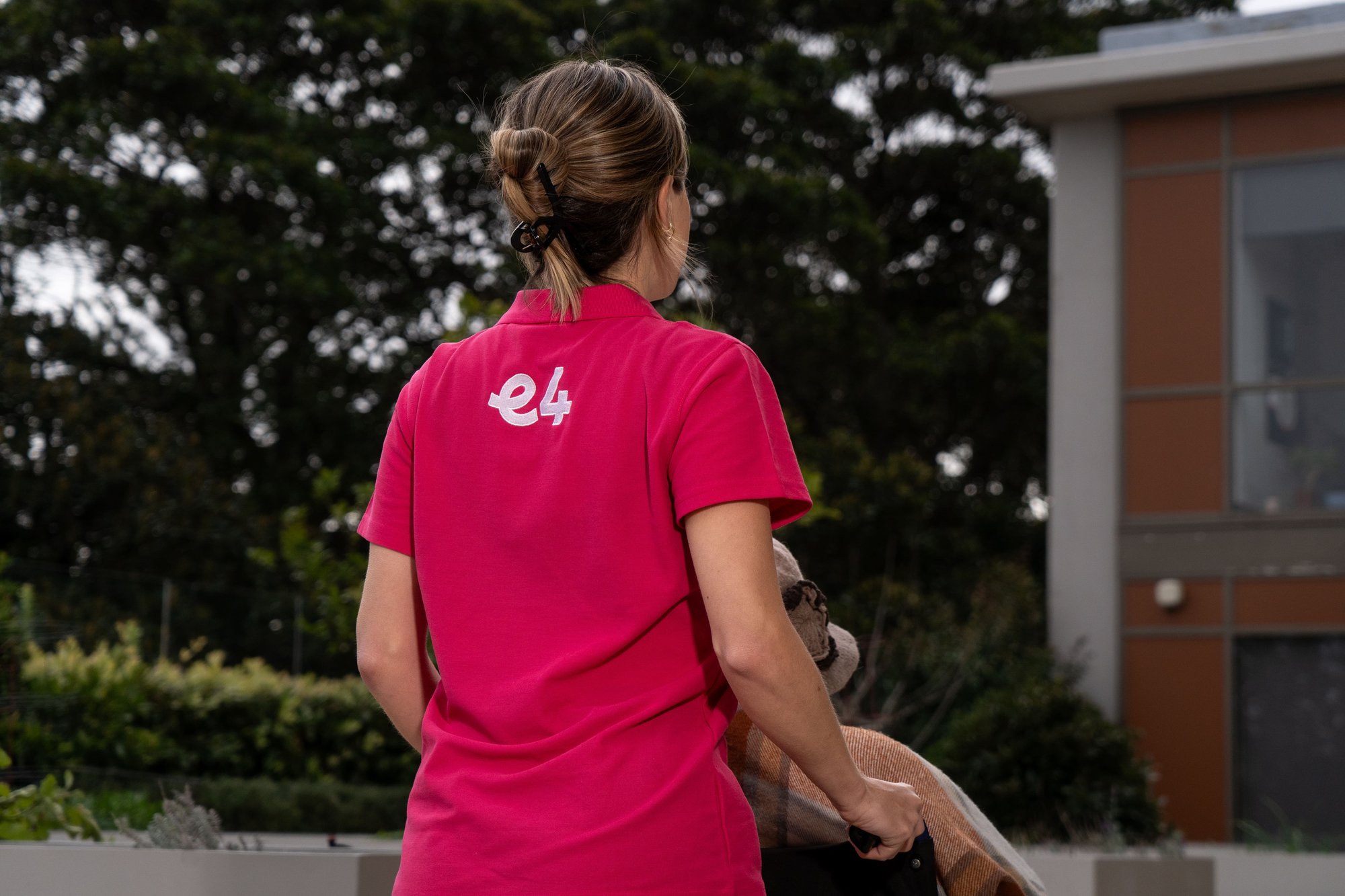Back of E4 nurse in pink uniform pushing resident in weelchair away 2