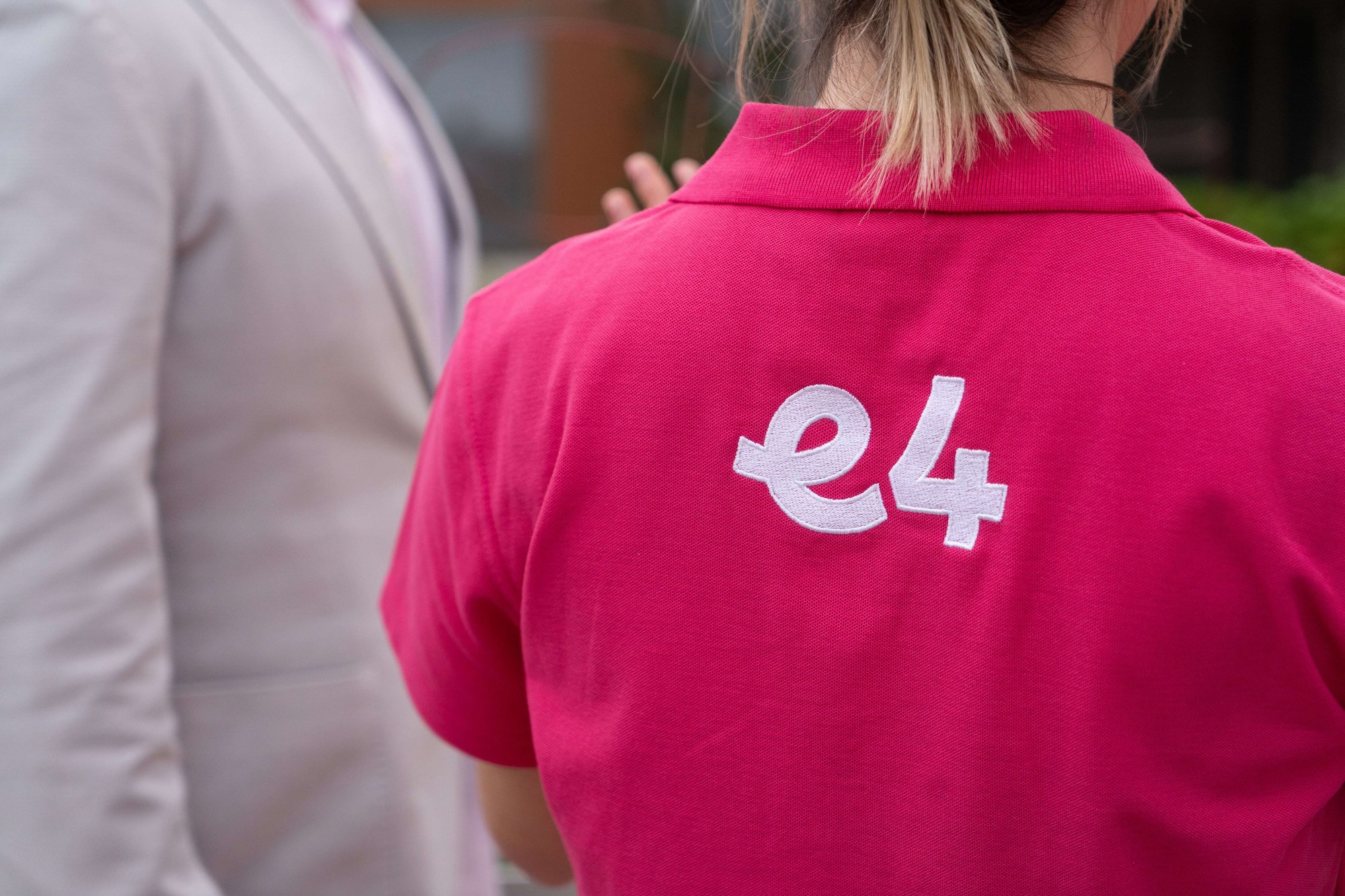 Back shot of nurse in pink uniform polo top with E4 embroidered