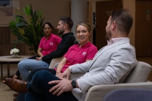 E4 nurse in pink uniform talking to Josh Hill on chairs with nurse and man in background
