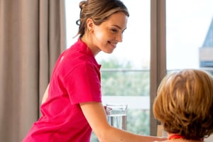 E4 nurse in pink uniform top serving resident food 10