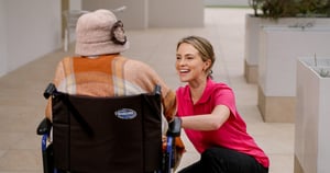 E4 nurse kneeling, smiling and talking to resident in wheelchair 4