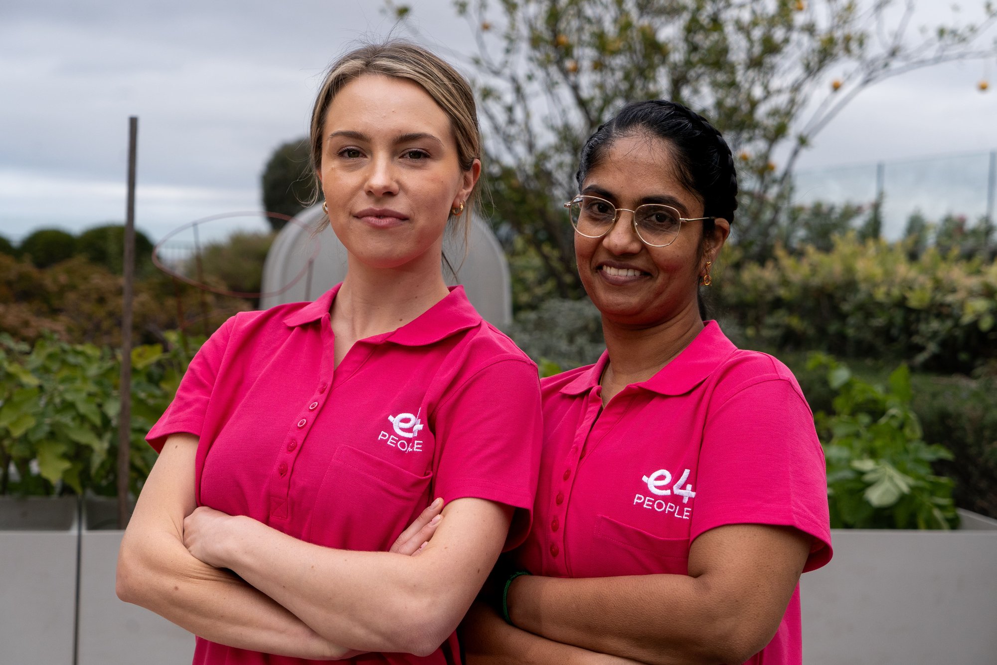 Two E4 nurses in pink uniform folded arms and smiling to camera 4