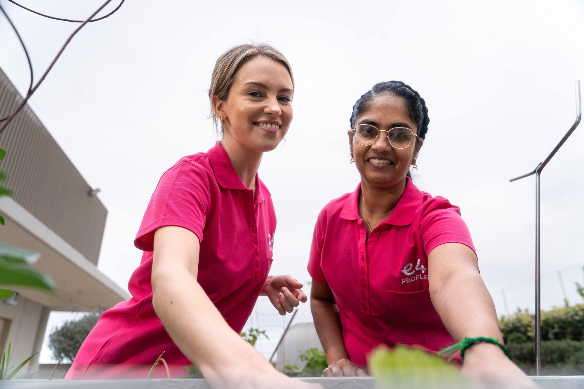 two E4 nurses learning over flower bed smiling to camera