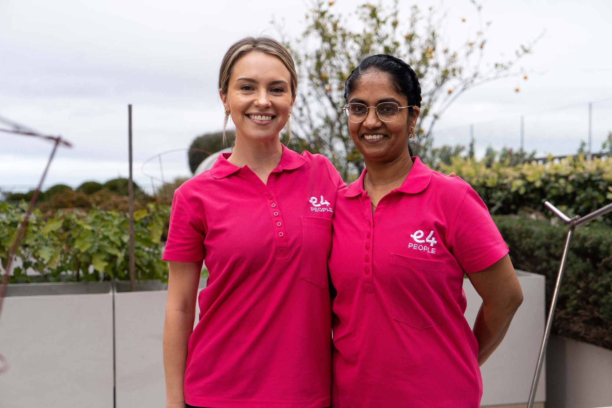 Two E4 nurses in pink uniform side hugging and smiling to camera 2